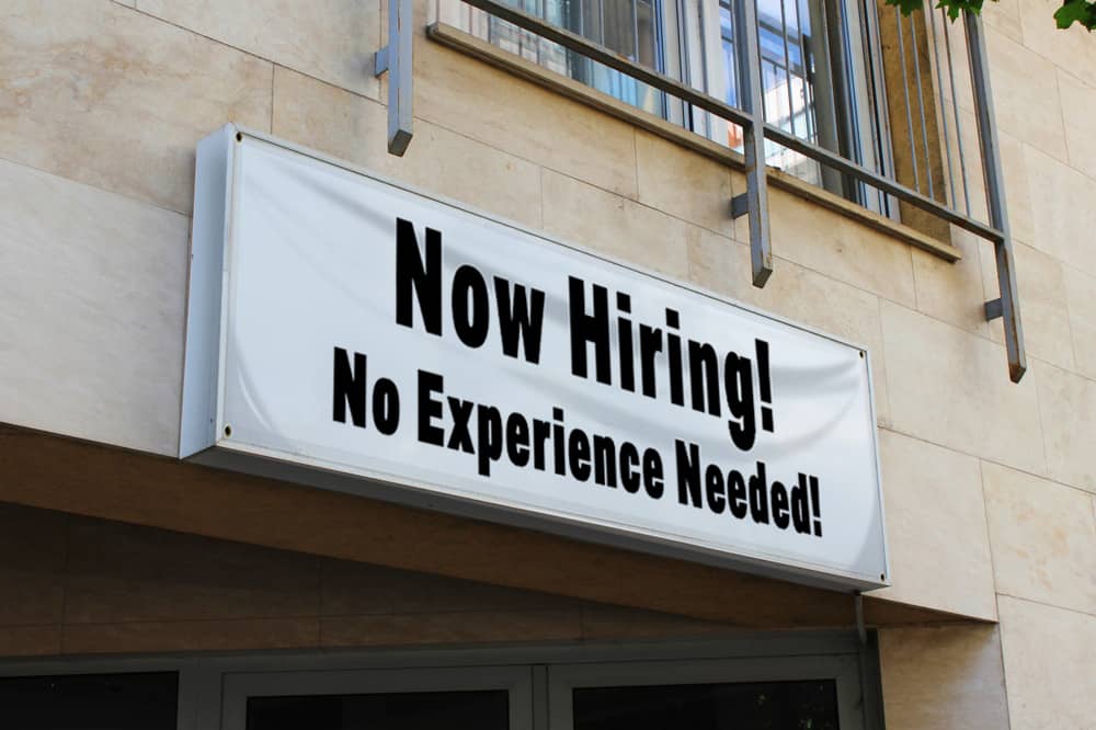 Now hiring economy banner hanging above a stores door.